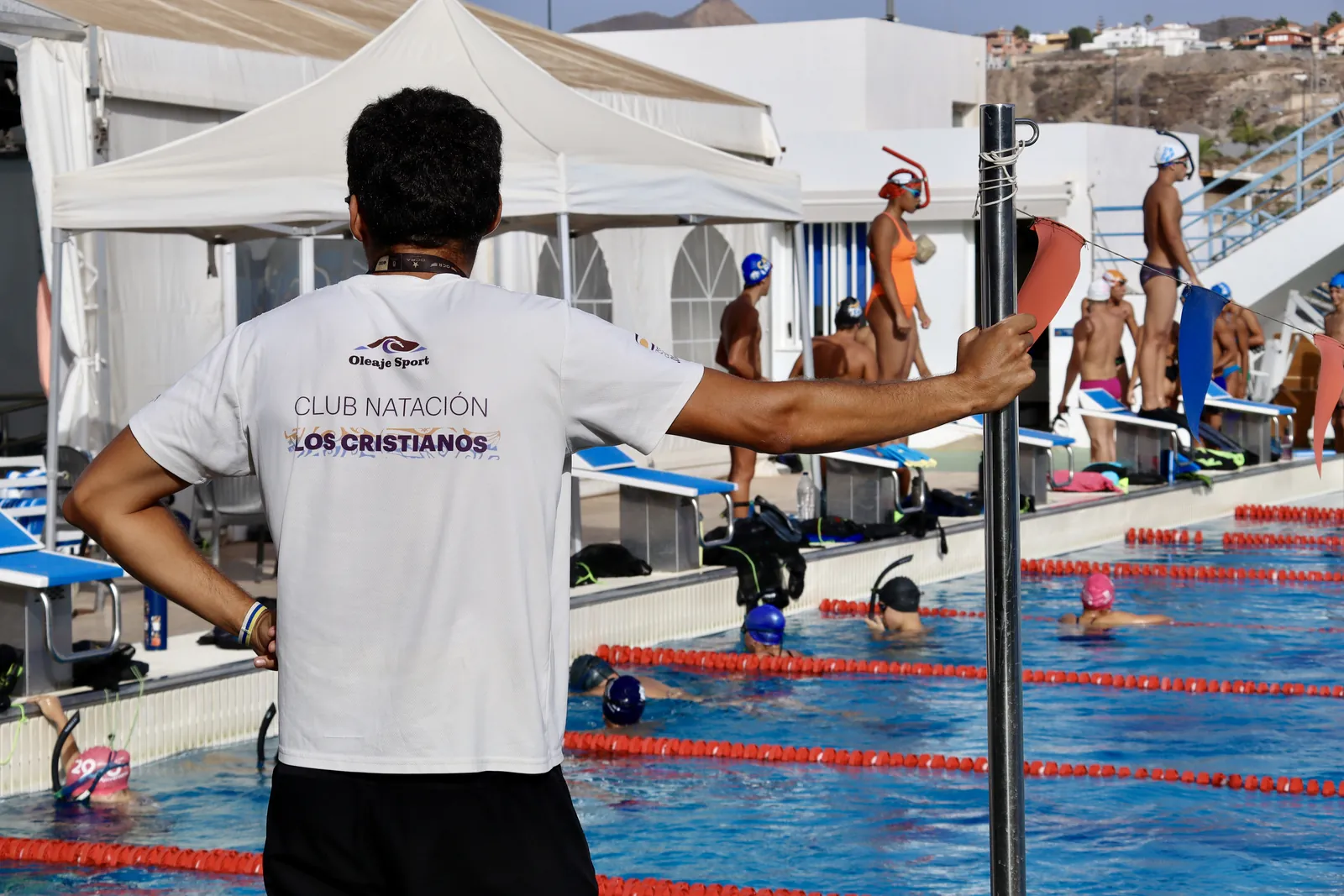 Entrenador dirigiendo la sesión al borde de la piscina